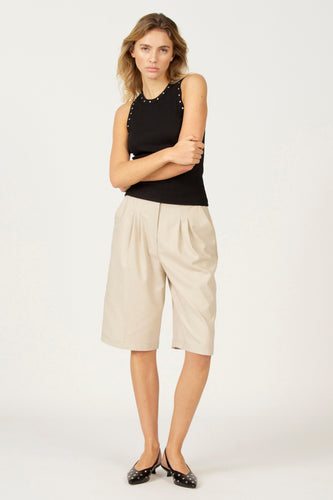 Zwarte singlet van Astrid Black Label, met zilverkleurige studs langs de halslijn, gedragen met kaki culotte en zwarte ballerina's.
