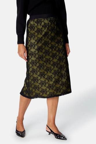 Jupe midi Astrid Black Label noire à motif floral, portée avec un pull noir.