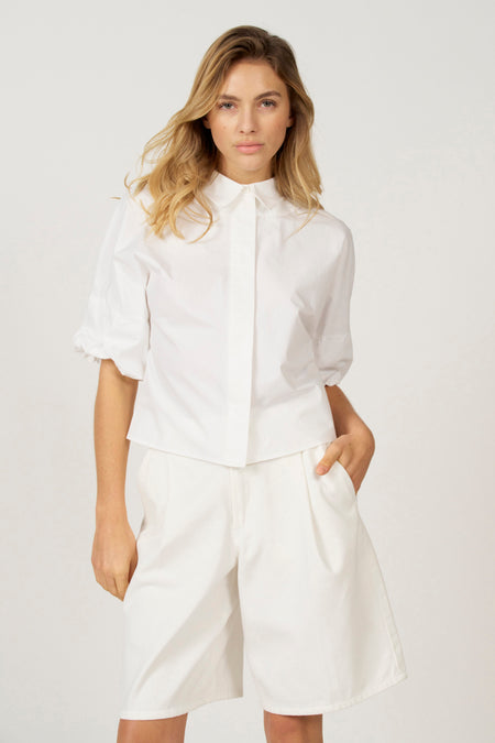 Blouse blanche d'Astrid Black Label, avec des manches longues et un col classique.