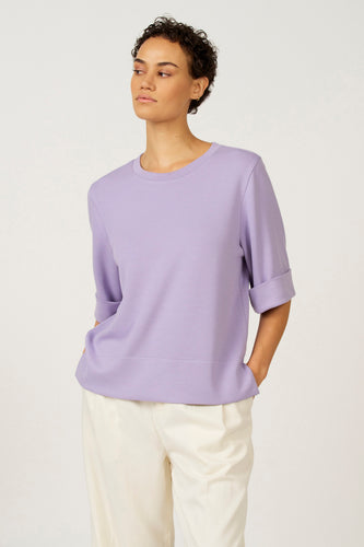 Paars T-shirt met korte mouwen van Astrid Black Label, met opgerolde mouwen en gecombineerd met een witte broek.
