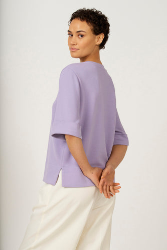 Paars T-shirt met korte mouwen van Astrid Black Label, met omgeslagen mouwen en witte broek.
