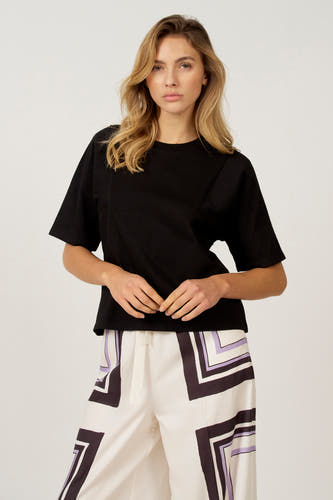 T-shirt noir à manches courtes d'Astrid Black Label, dos, associé à un pantalon avec un motif géométrique.