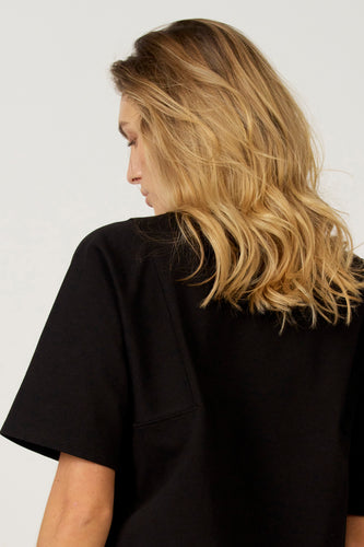 Zwart T-shirt met korte mouwen van Astrid Black Label, gezien vanaf de achterkant, met een rechte pasvorm en een eenvoudige pocketdetail.
