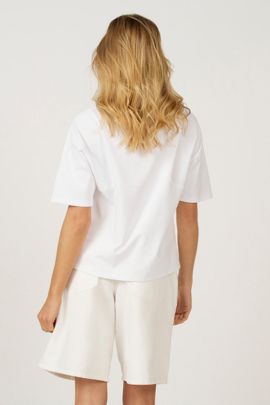 Wit T-shirt met korte mouwen van Astrid Black Label, gezien van achteren, gecombineerd met een witte korte broek.