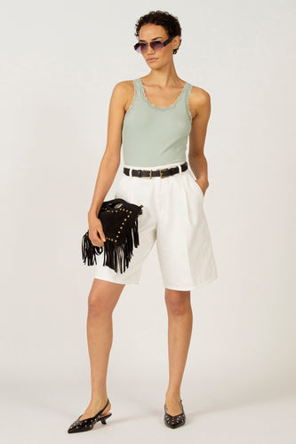 Groene singlet van Astrid Black Label, met kanten details langs de halslijn, gecombineerd met witte shorts en zwarte riem.
