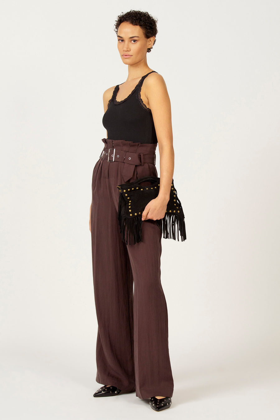 Zwarte singlet van Astrid Black Label met kanten details langs de halslijn, gedragen met bruine, hoge taille broek en een zwarte clutch.