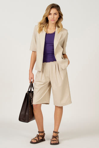 Robe simple noire d'Astrid Black Label, portée sous un blazer beige et des bermudas coordonnés, avec des sandales brunes et une grande sacoche.