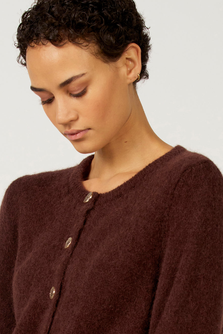 Vrouw draagt bruin wollen vest.
