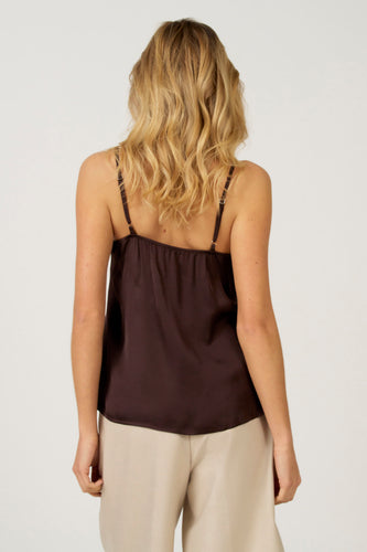 Achterkant van een vrouw met blond haar, een bruine top en beige broek.