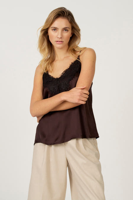 Blouse sans manches brune Astrid Black Label avec des détails noirs, associée à une jupe beige.
