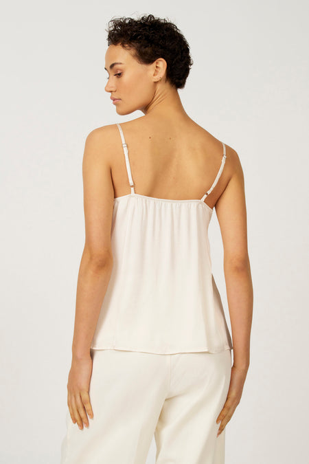 Model in crème satijnen top en broek, van achteren gezien.