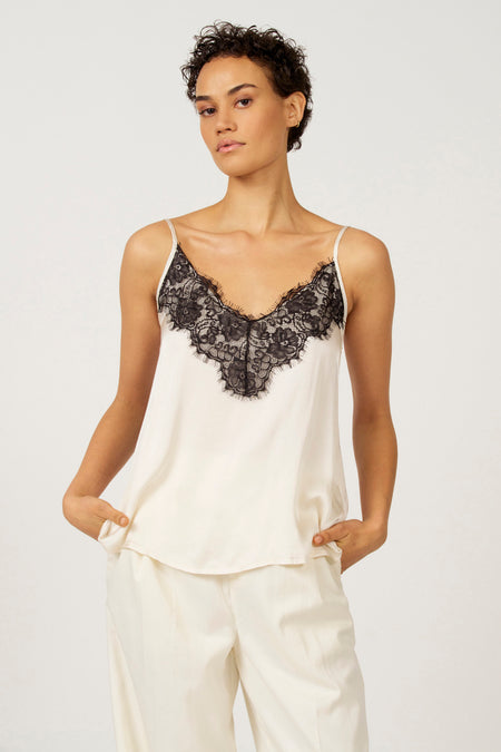 Vrouw in witte pyjama met zwarte kanten top, staand.