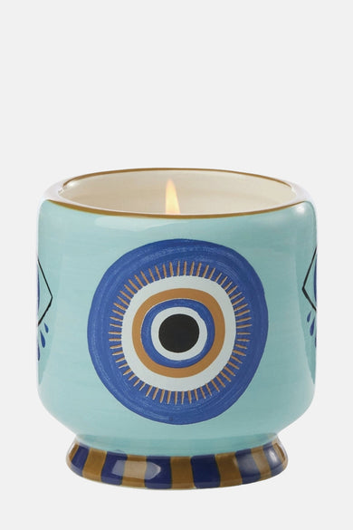 Bougie multicolore de PADDY WAX, avec un motif d'œil frappant en bleu, or et noir.