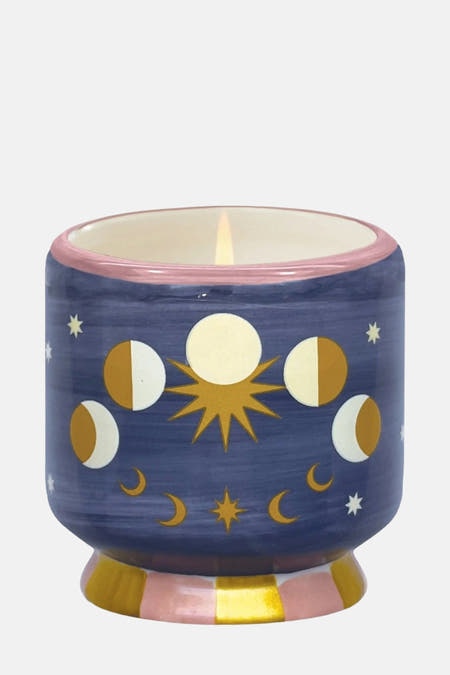 Bougie multicolore de PADDY WAX avec des phases de lune et un motif d'étoiles sur un fond bleu.