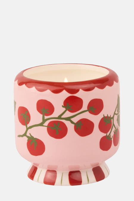 Bougie rouge de PADDY WAX avec un imprimé tomate et une bordure rouge en haut, sur un pied rayé.