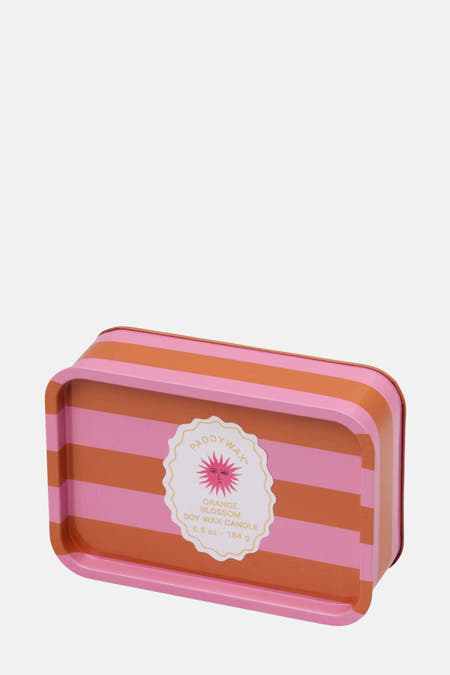 Bougie rose de PADDY WAX, rayée d'accentuations orange et dotée d'un étiquet décoratif.