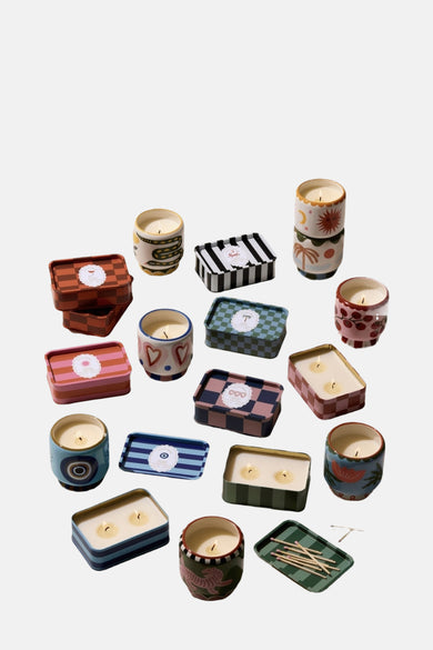 Bougie rose de PADDY WAX, avec divers pots colorés et décoratifs et des supports céramiques, y compris des allumettes.