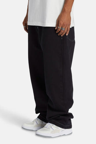 Jean délavé noir de DC SHOES, avec une coupe décontractée et des baskets blanches.