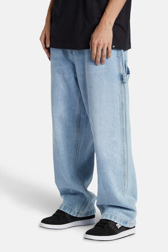 Jean décontracté en denim bleu clair de DC SHOES, avec une coupe décontractée et des chaussures noires.