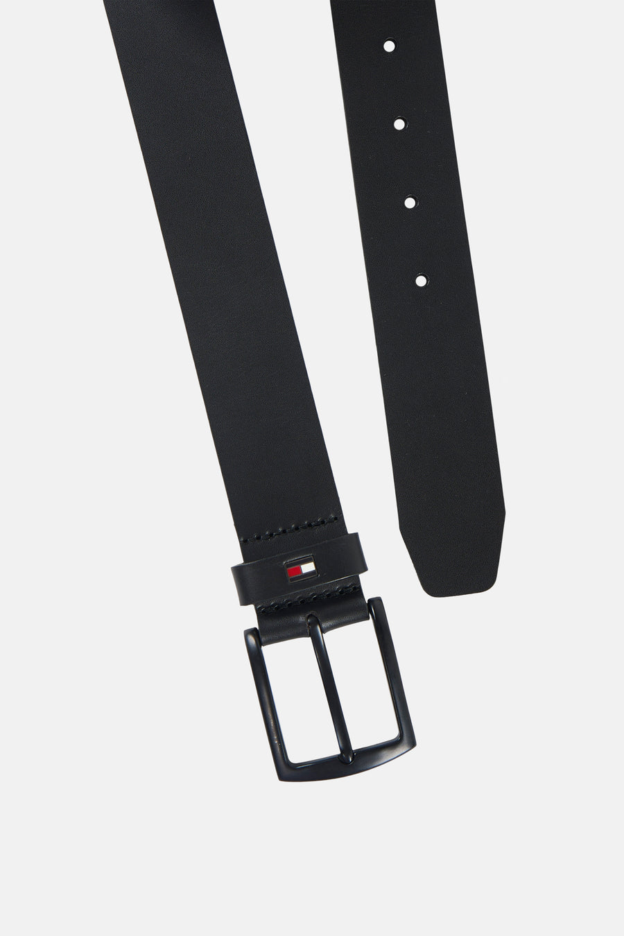 Ceinture noire TOMMY JEANS, présentée en diagonale, avec une boucle métallique, des perforations et le logo drapeau sur le passant.