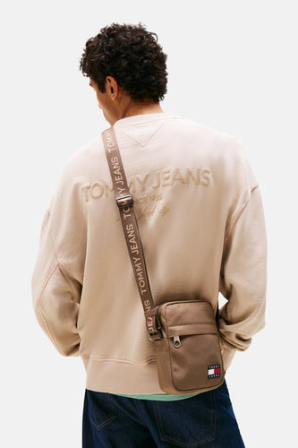 Man met beige sweater en bruine Tommy Jeans tas, rug gezien.