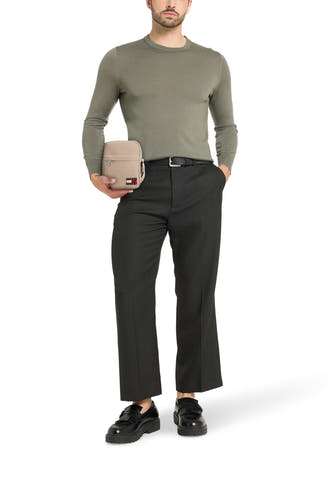 Beige schoudertas van TOMMY JEANS, gedragen met een olijfgroene trui, zwarte pantalon en loafers.