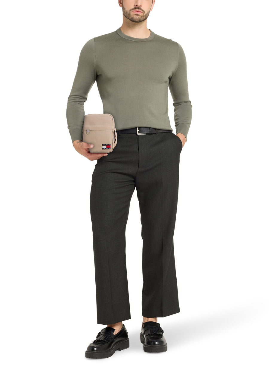 Beige schoudertas van TOMMY JEANS, gedragen met een olijfgroene trui, zwarte pantalon en loafers.
