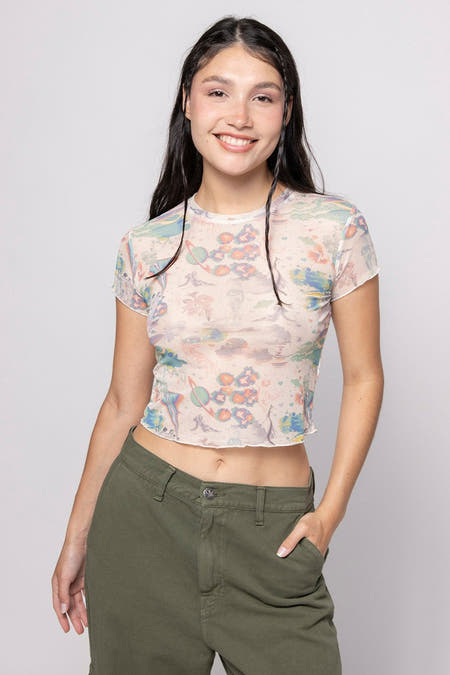 T-shirt écru de KAOTIKO, avec une impression all-over de planètes, porté avec un pantalon vert.