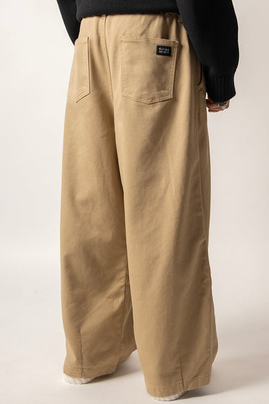 Pantalon beige de KAOTIKO, avec une coupe décontractée, des poches arrière et un étiquette marque noire.