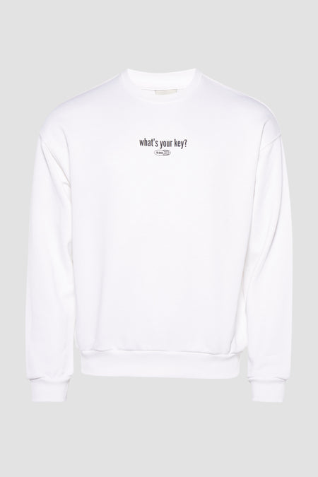 Pull-over blanc de KAOTIKO avec impression textuelle sur la poitrine, contre un fond gris clair.