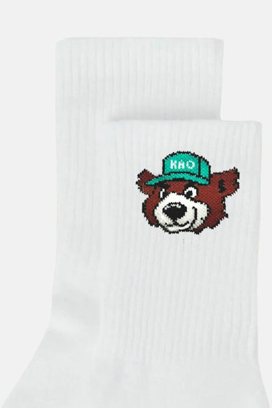 Witte sokken met geborduurde bruine beer met groene pet.
