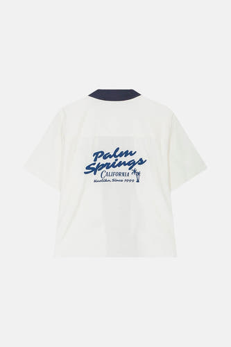 Chemise blanche à manches courtes de KAOTIKO, avec imprimé bleu "Palm Springs California" sur le dos.