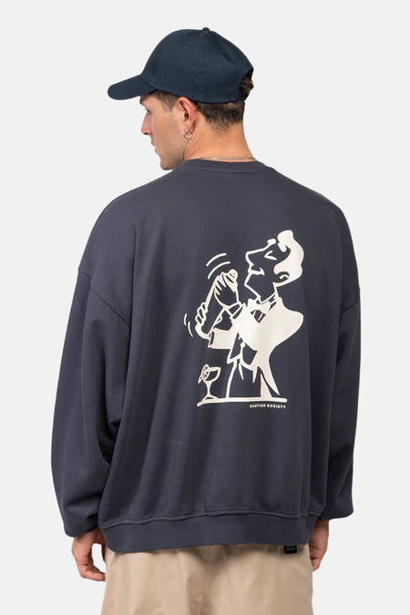 Pull-over bleu de KAOTIKO, avec une illustration blanche d'un barman sur le dos.