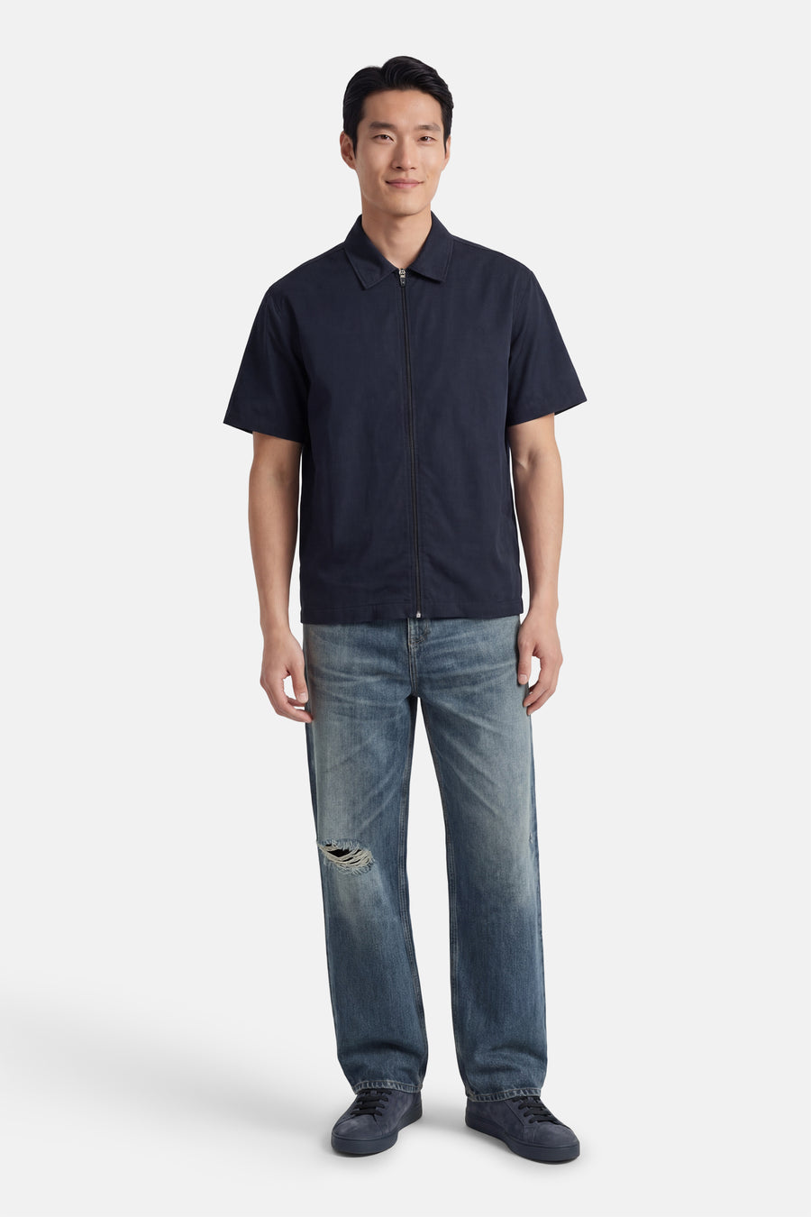 Chemise bleue à manches courtes de Kaotiko, avec une fermeture éclair et portée avec un jean bleu.
