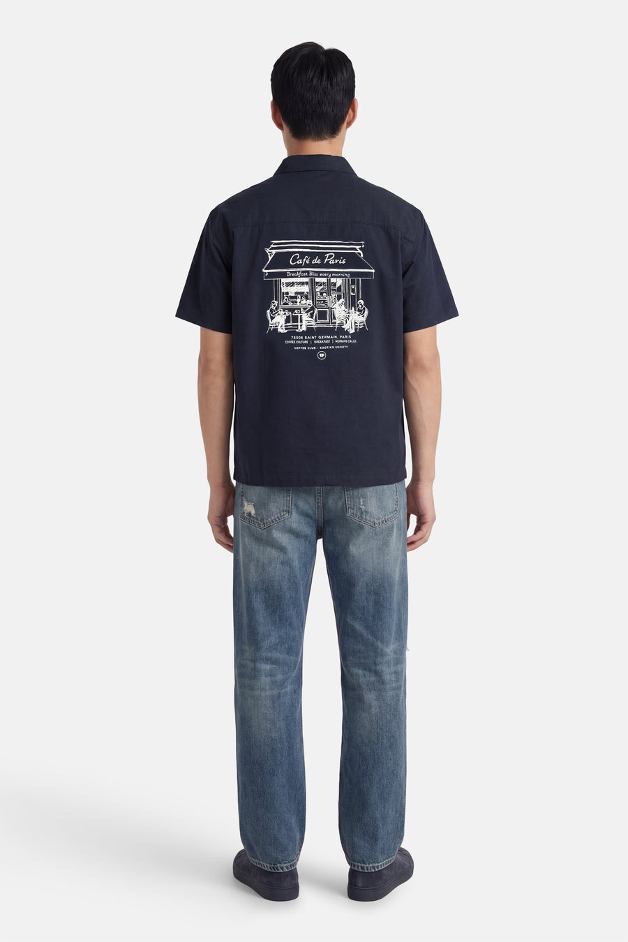 Chemise bleue à manches courtes de KAOTIKO, avec imprimé blanc Café de Paris au dos, à combiner avec un jean.