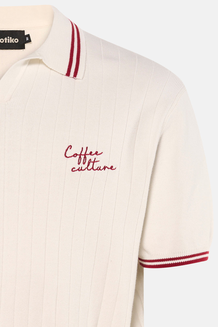 Polo blanche à manches courtes de KAOTIKO avec texture côtelée et texte brodé.