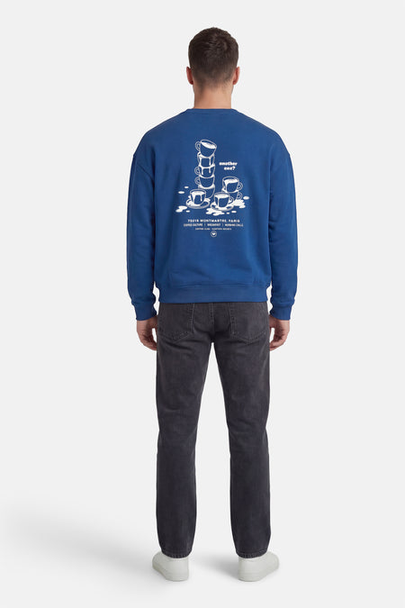 Pull bleu à col rond de KAOTIKO, avec imprimé de tasses à café et texte dans le dos.