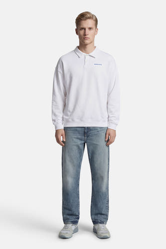 Pull blanc de KAOTIKO, à manches longues, porté avec un jean bleu et des baskets grises.