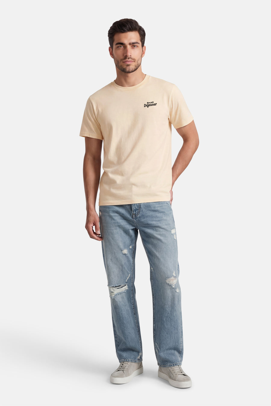 T-shirt écru de KAOTIKO, à manches courtes et avec un petit imprimé texte, combiné avec un jean déchiré et des baskets.