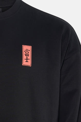 Sweatshirt noir de KAOTIKO, avec un patch rectangulaire avec des caractères japonais sur la poitrine.