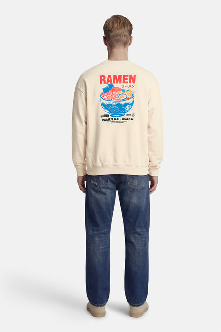 Pull écru de KAOTIKO, avec un imprimé graphique d'un bol de ramen dans le dos.