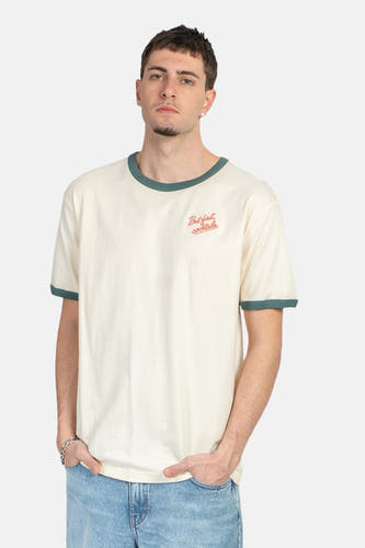 T-shirt écru de KAOTIKO avec bords verts et inscription 'But first cocktails', porté avec un jean.