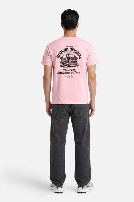 T-shirt rose de KAOTIKO avec un imprimé noir dans le dos d'un grand sandwich et le texte 'HUDSONS ORIGINAL'.