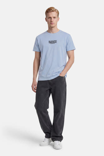 T-shirt bleu de KAOTIKO avec imprimé texte 'HUDSONS ORIGINAL', porté avec un pantalon foncé et des baskets blanches.