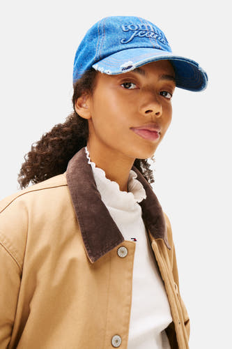 Casquette bleue marine de Tommy Jeans, avec un bord froncé et portée avec une veste brune.