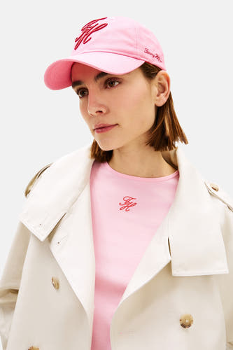 Casquette rose de TOMMY JEANS, avec logo brodé et portée avec un t-shirt rose sous un trench-coat beige.
