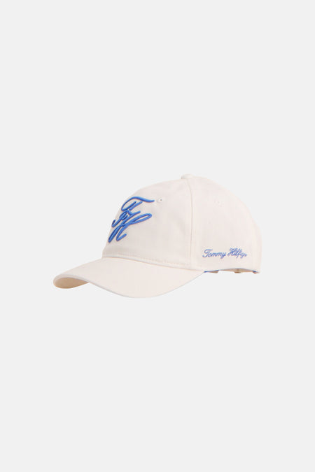 Casquette blanche TOMMY JEANS avec logo bleu brodé sur le devant et signature Tommy Hilfiger sur le côté, en vue latérale.