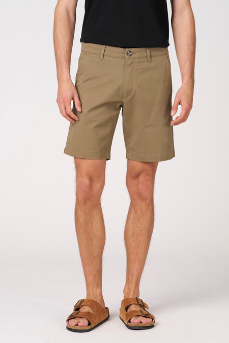Khaki bermuda van Bruce & Butler, gedragen met bruine sandalen en een zwart shirt.