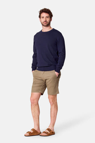 Shorts de Bruce & Butler, portés avec un pull bleu marine et des sandales brunes.