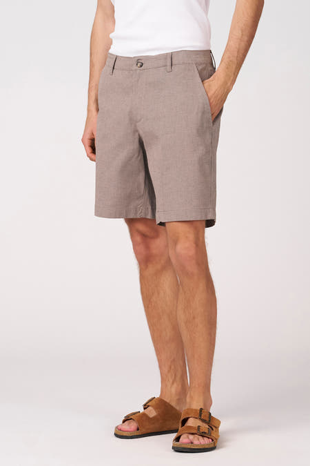 Beige bermuda van Bruce & Butler, met een subtiel patroon en een casual stijl, gedragen met een wit shirt en sandalen.